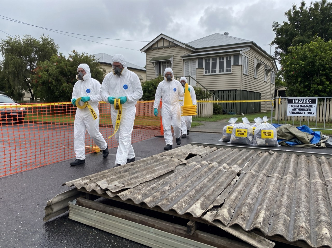 Storm-damaged roof sheeting with crew arriving to establish hazard barriers
