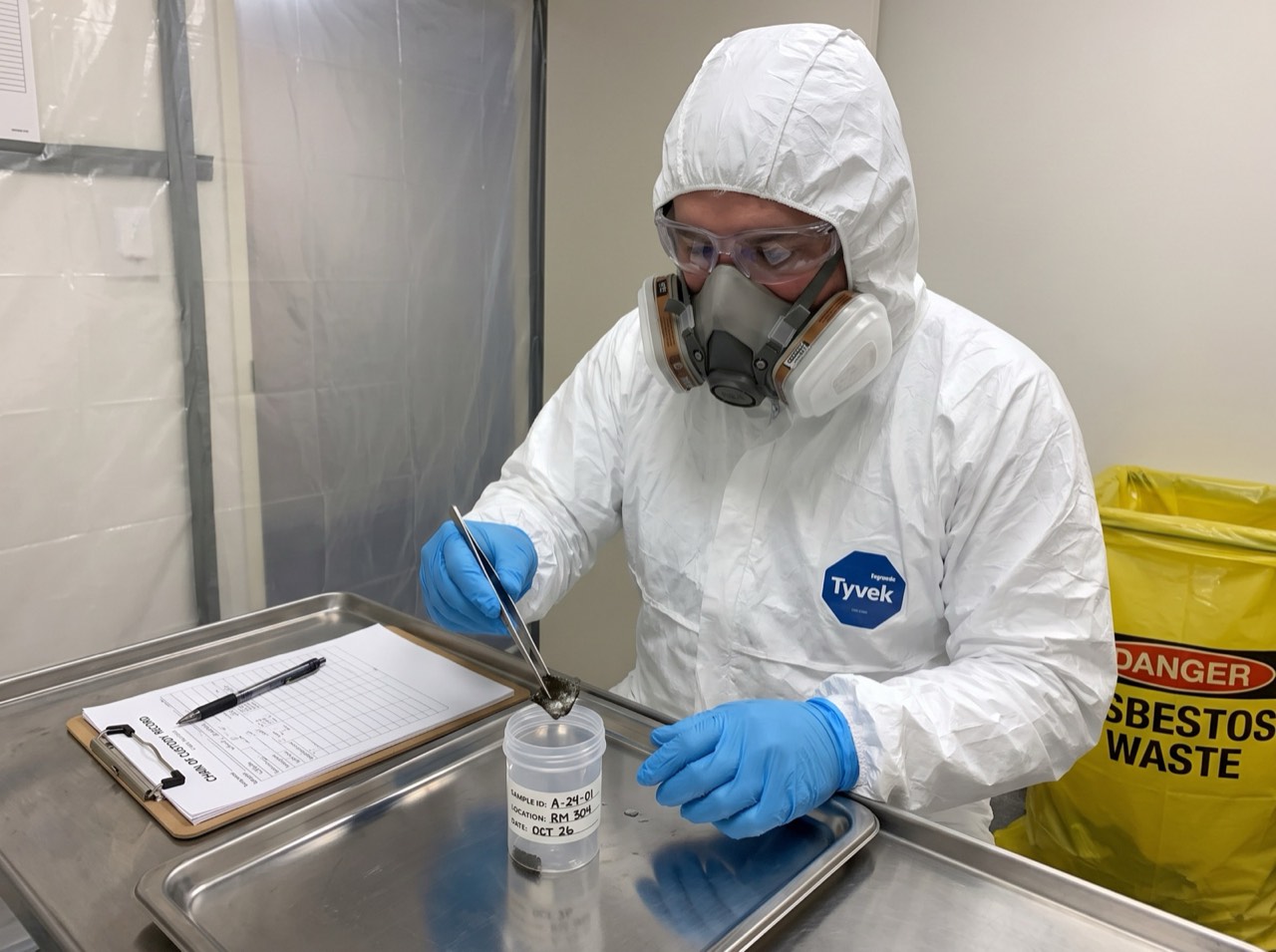 Technician in PPE taking a sample and sealing it in a labelled container